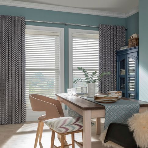 Dining room with patterned Curtains in eclipse denim fabric layered over Natural Stone Faux Wood Venetian Blind