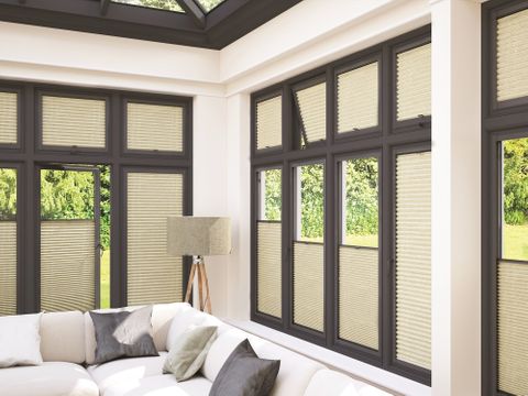 Modern conservatory with dark frame windows dressed with cream thermals blinds