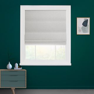 Moondust coloured roman curtains fitted on a large rectangular shaped window in a room with green decorated walls