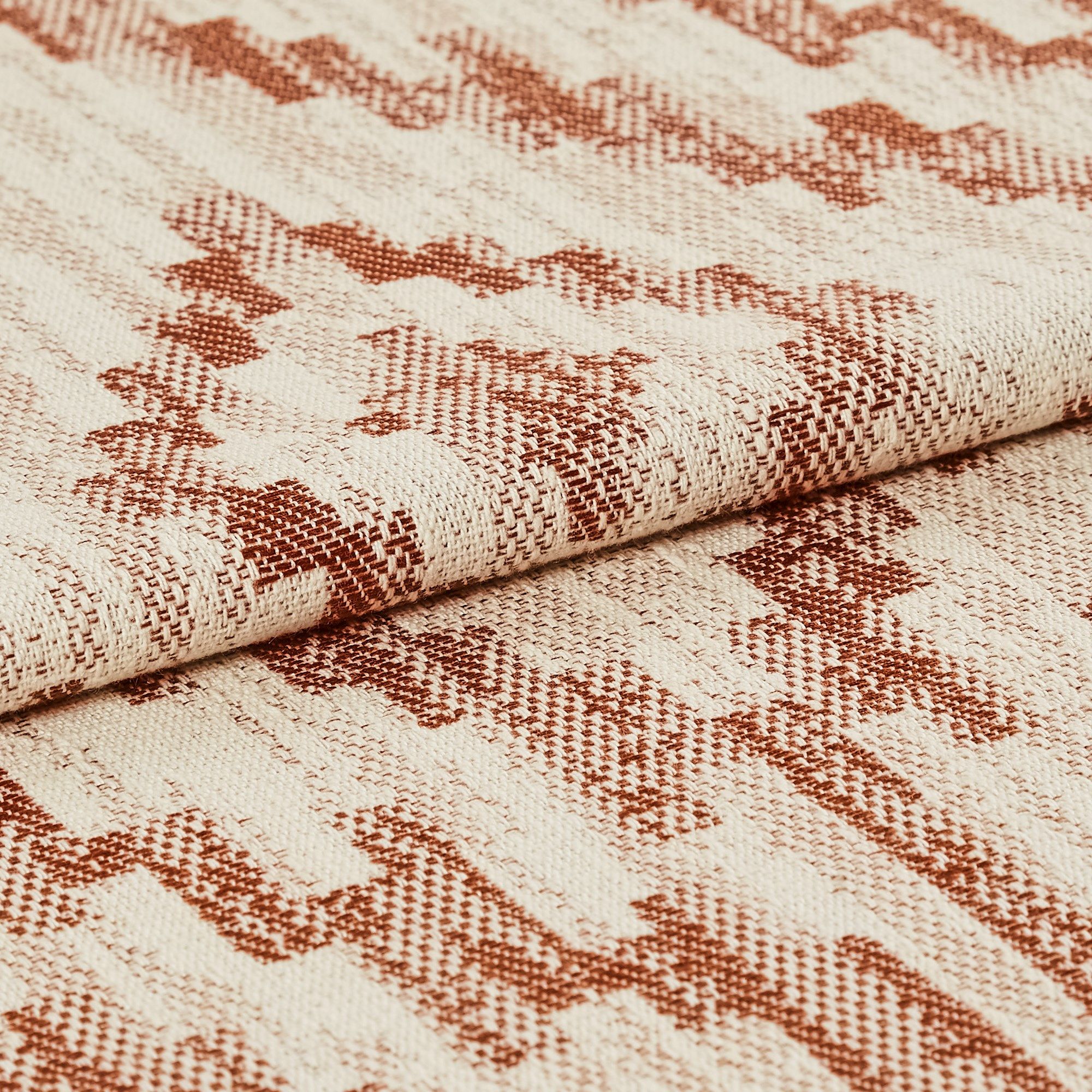 Cream coloured base fabric which is patterned in a repeating tribal design in dark orange 