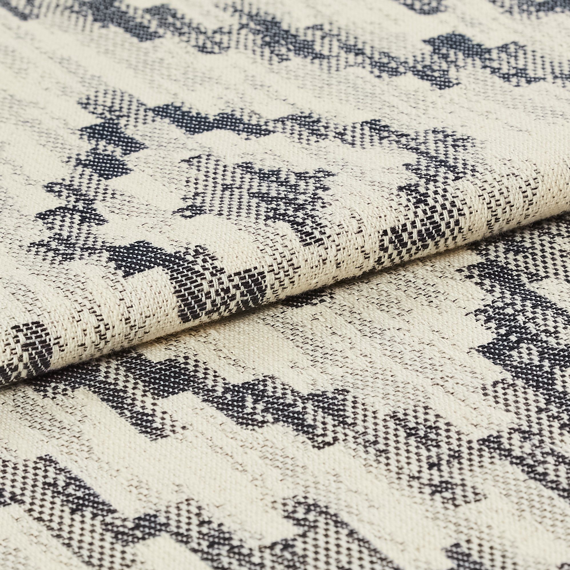 Navy blue and white coloured folded material with a repeating geometric pattern