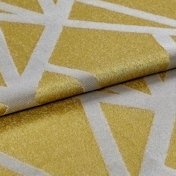 Shiny gold coloured fabric which is folded over with a repeating geometric pattern in bright white