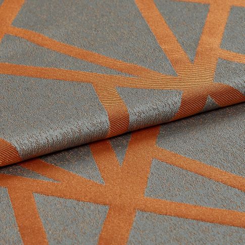 The material is dark grey with a slight shine to it and layered with geometric designs that criss cross in thick lines of orange