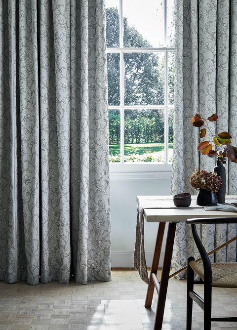 Close up detail of light sage green  curtains featuring delicate embroidery in a dining room