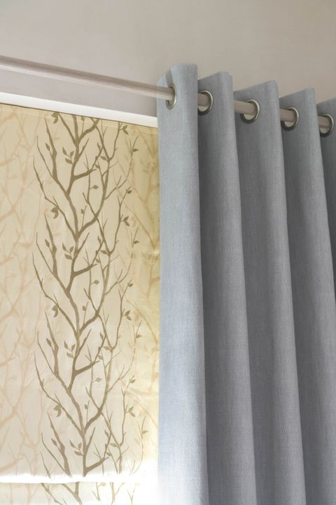 Close up of Bailey Cloudy eyelet  curtains and Pyrus Cream Roman blinds in bedroom