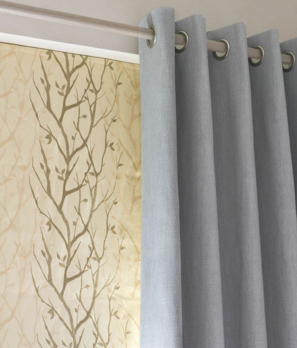 Close up of Bailey Cloudy eyelet  curtains and Pyrus Cream Roman blinds in bedroom
