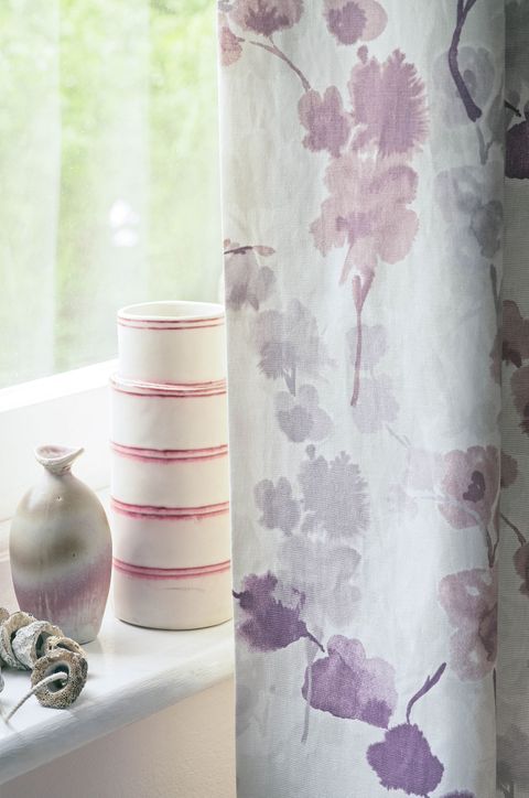Close up detail of vases on windowsill and purple floral curtain