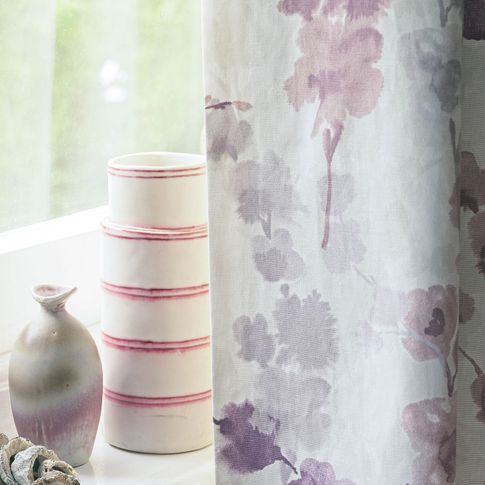 Close up detail of vases on windowsill and purple floral curtain