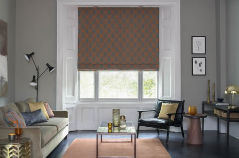 Dimension Ember geometrical patterned Roman blinds in grey and copper in a grey living room