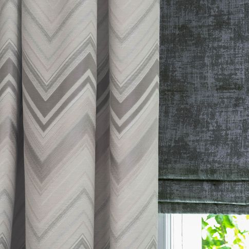 Close up of grey pattern curtains and black roman blinds in living room