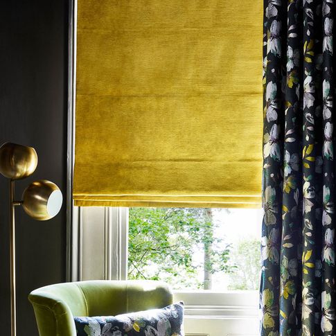 Close up detail of living room window with floral curtains and yellow velvet Roman blind
