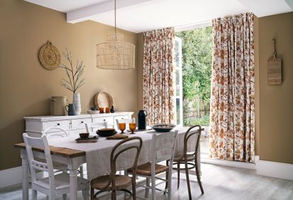 Rustic dining room with french doors opening onto the garden. Floral curtains at the window