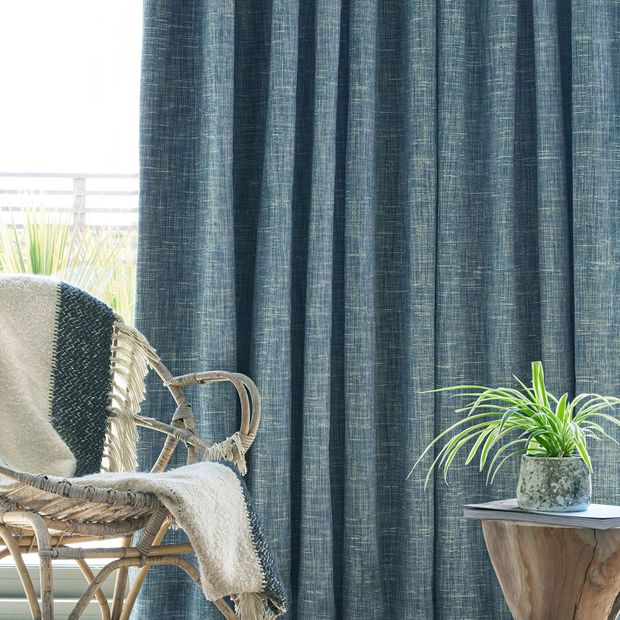 Close up of wicker chair in front of window with Haddie Ocean curtains