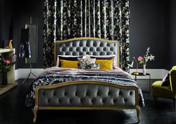 Dark painted bedroom with floral curtains behind a double bed