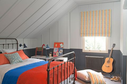 Striped roman blinds with mustard, orange and light blue colors in an attic bedroom