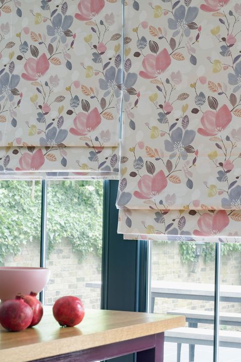 Layers of a Roman blind featuring a lavender, rose and yellow coloured floral pattern hang neatly in front of a window.