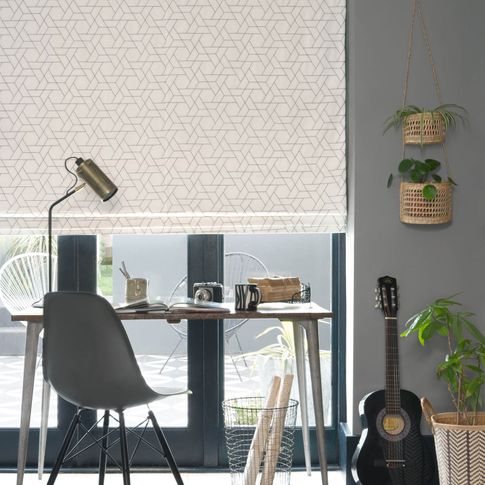 Layered roman blinds featuring Geometric grey shapes on a neutral white background hanging neatly on window of home office. 