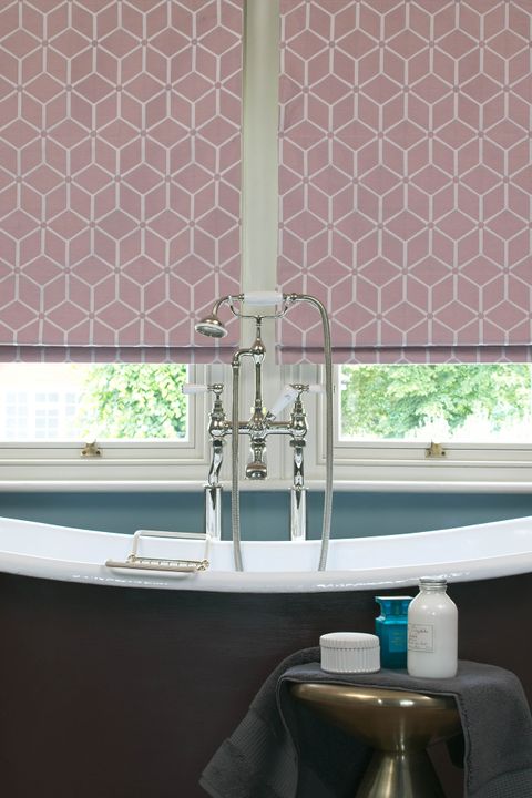 Close up of roman blinds in pink color featuring geometric shapes in a bathroom.