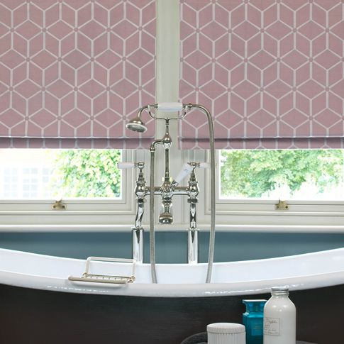 Close up of roman blinds in pink color featuring geometric shapes in a bathroom.