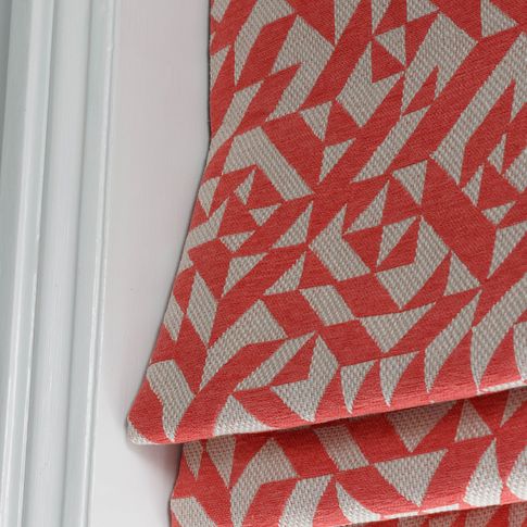 Close up of roman blinds featuring linear print in coral red and white colour