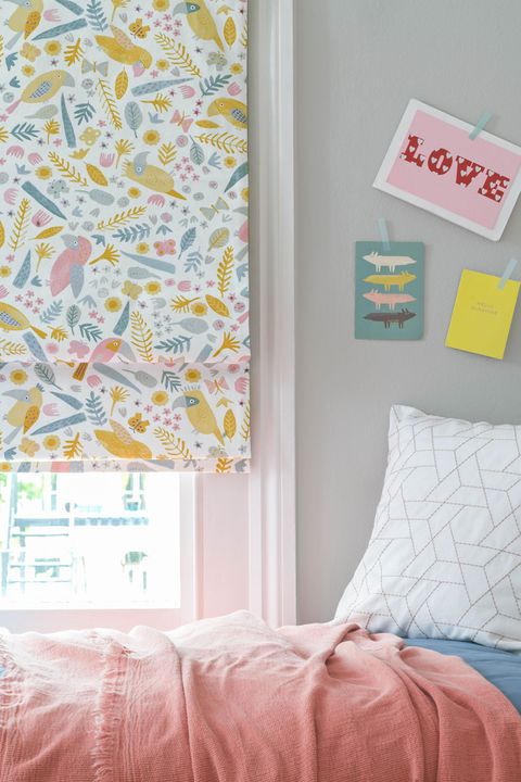 Corner view of kids bedroom window dressed with roman blinds featuring tucan print on white background