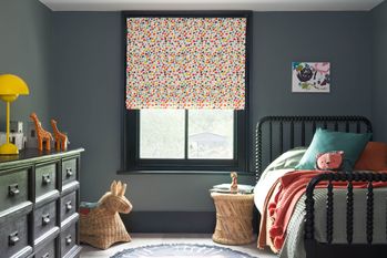 A grey children's bedroom with multi-coloured dotty Roman blinds
