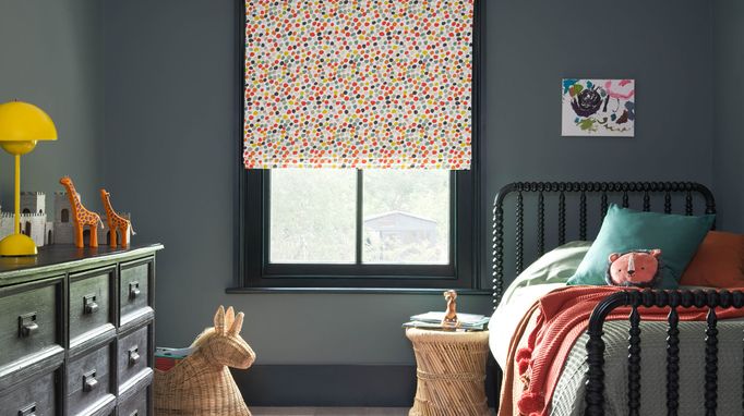 A grey children's bedroom with multi-coloured dotty Roman blinds