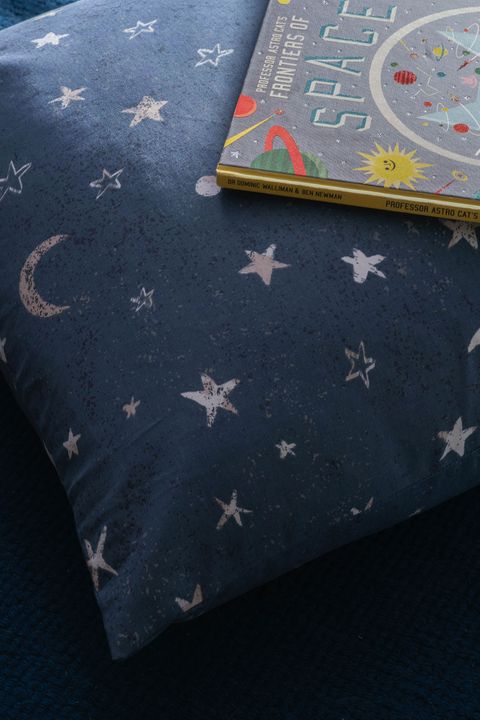 Close up detail of space theme cushion cover with stars and moon motifs
