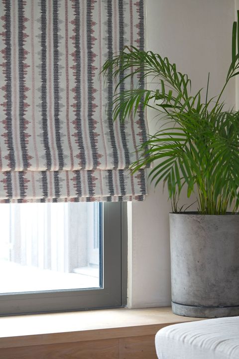 View of window dressed with a tribal-inspired Roman blind in red and brown accents on a white background