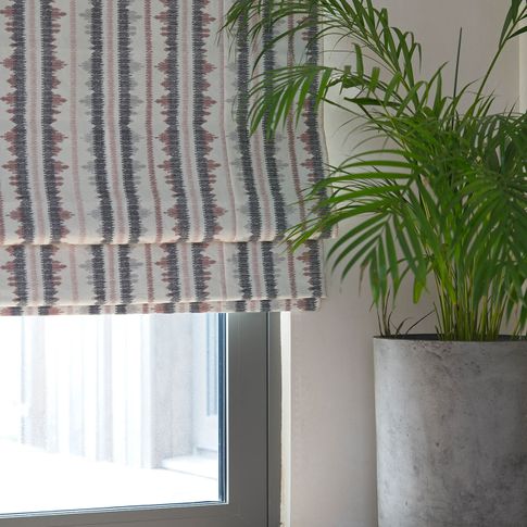 View of window dressed with a tribal-inspired Roman blind in red and brown accents on a white background