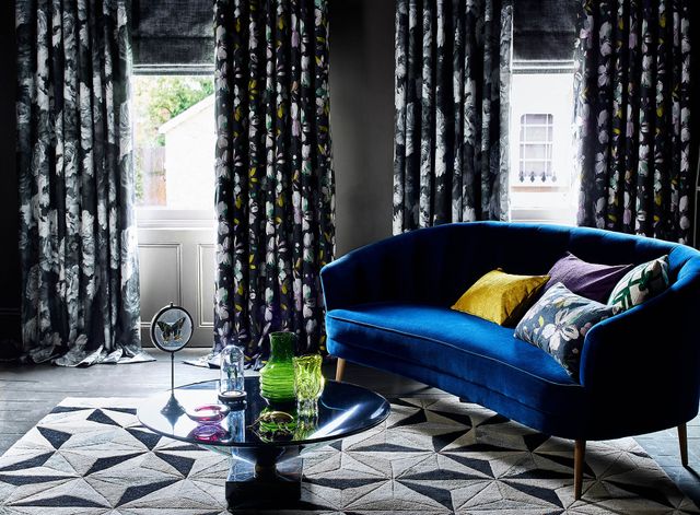 Windows in living room dressed with charcoal Roman blinds under a floral print curtains