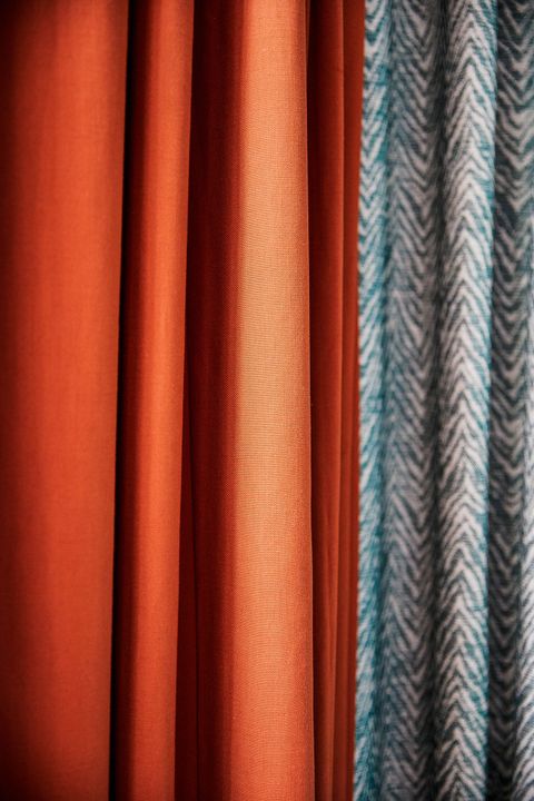 Close up detail of burnt orange curtain and green geometric print curtain