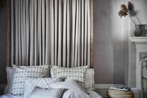 Grey striped curtains on a bed headboard and few patterned, plain and geometric print cushions have been placed nicely on bed