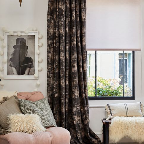A black framed window with a textured grey curtain and pink Roller blind