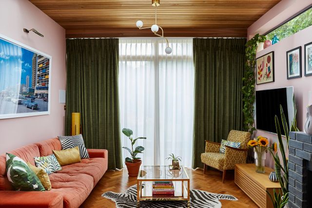 A pink 70s style living room with green curtains