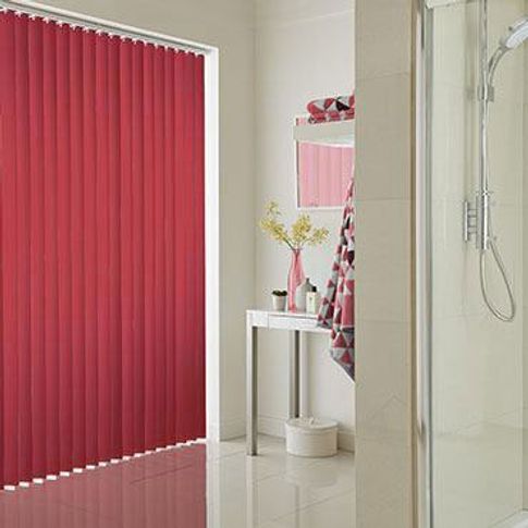 Deep red coloured vertical blind fitted to a wide window in a bathroom decorated in white