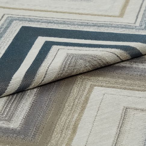 Folded fabric with a white base but is patterned with rectangular outlines in blue, grey and beige