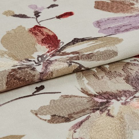 Flowers and twigs decorate the white coloured fabric in a variety of colours in a style that looks hand stitched