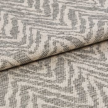 Beige coloured folded fabric that is decorated with a repeating wave like pattern in light grey