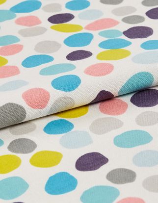 Odd shaped circles in different colours in a repeating pattern on white fabric