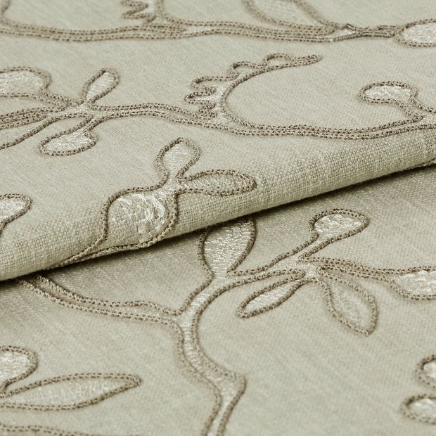 Neutral coloured fabric which has been folded is decorated with a repeating leaf and stem design 