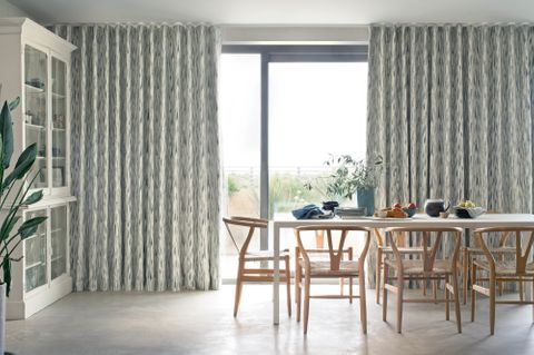 bifold doors of a dining room dressed with print pattern cream curtains