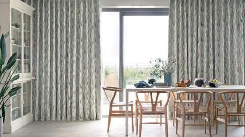 bifold doors of a dining room dressed with print pattern cream curtains