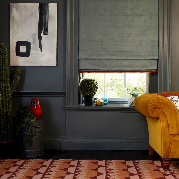 cley donkey roman blind with collette vixen fringing in a grey living room with an orange sofa and cactii