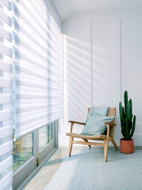 A wide window featuring a white Day & Night roller blinds and a chair