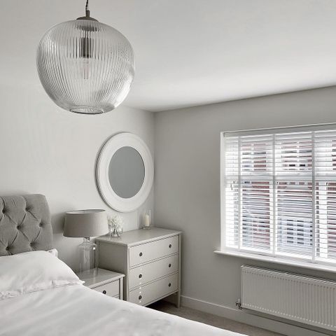 Grey and white bedroom, featuring white wooden venetian blinds with white tape 