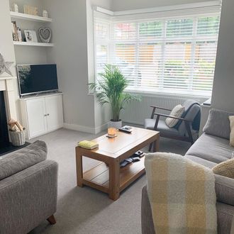 white wooden blinds in a living room with grey sofa