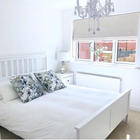 beige roman blinds in a white bedroom