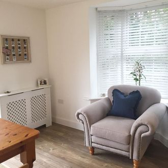 white wooden blinds in a living room. A cream sofa has been placed in the room
