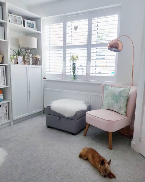 White shutters in living room with pink chair and grey storage chair